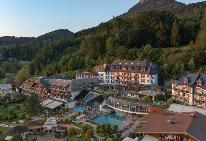 Aerial view of a scenic hotel surrounded by lush greenery and mountains.