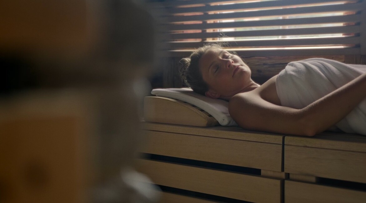 Pärchen im Innenpool des 4 Sterne Superior Wellnesshotel Waldhof Fuschlsee Resort mit Blick auf den Außenpool.