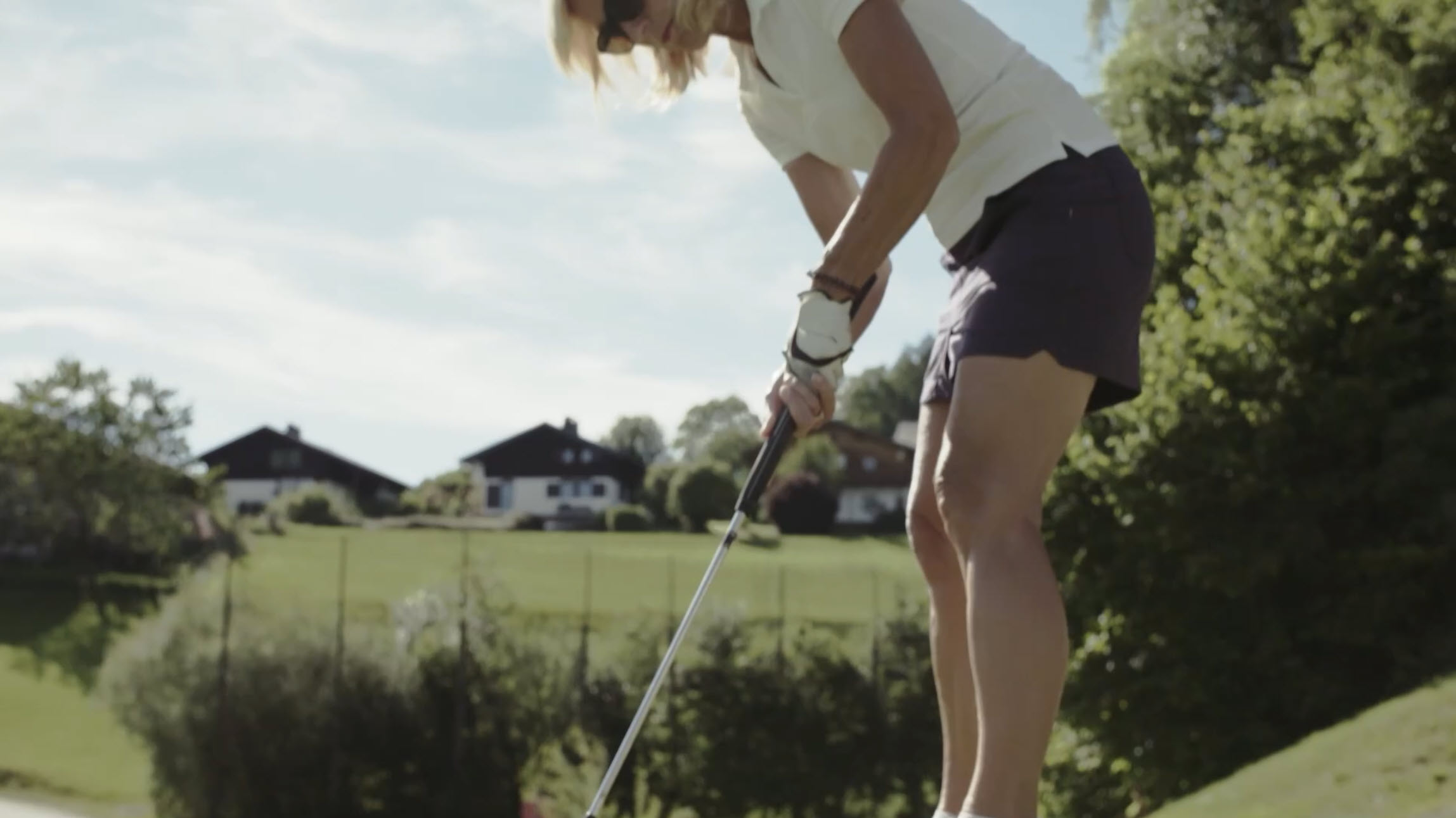 A person playing golf on a sunny day, surrounded by lush greenery and scenic landscape.