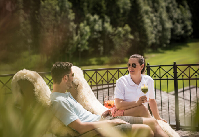 A couple relaxes outdoors with drinks at Waldhof Alm.