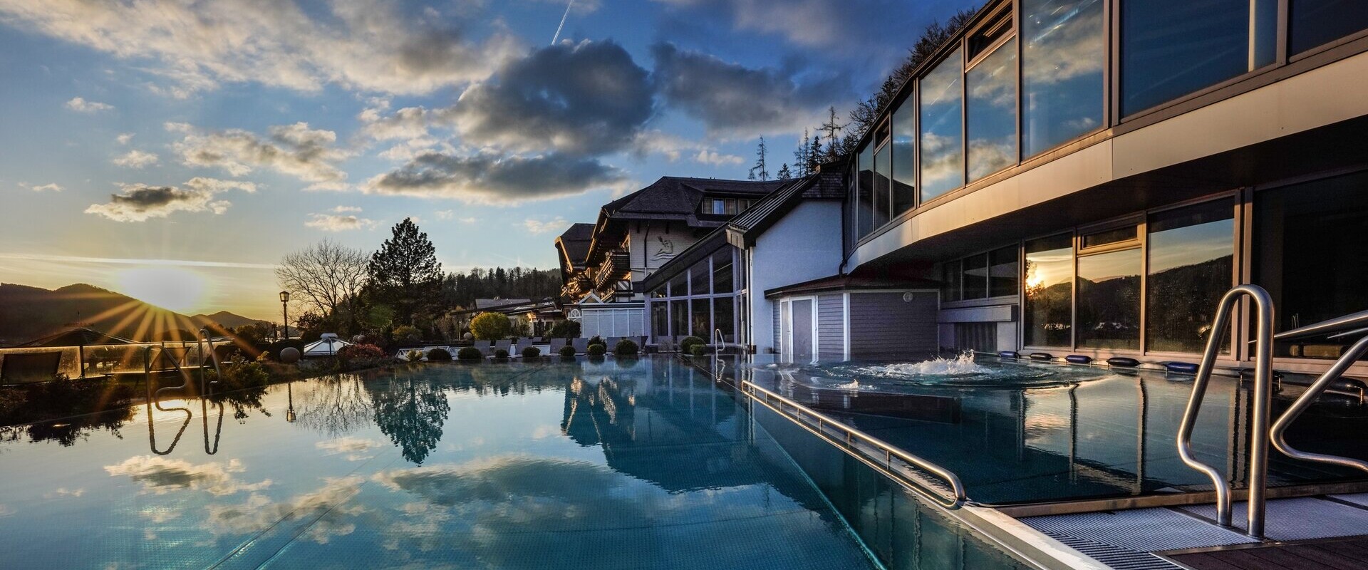 Outdoor pool reflecting the sunset and clouds.