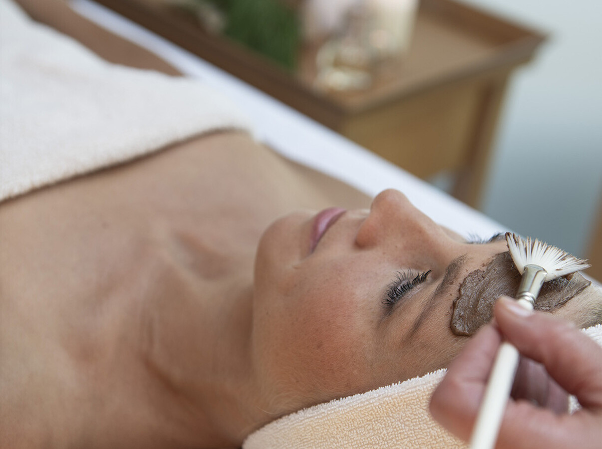 A person receiving a relaxing facial treatment with a brush.