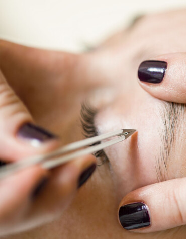 Eyebrow being carefully shaped with tweezers during a beauty treatment.