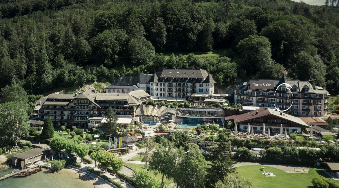 Aerial view of a lush, scenic lakeside hotel surrounded by trees, with a highlighted "Turm Suite" section.