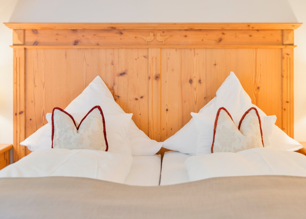 A cozy bed with white pillows and wooden headboard in a serene room.