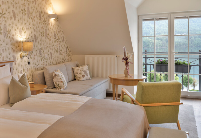 Großzügiges Zimmer mit Balkon und Blick zum See im Hotel Ebner's Waldhof am Fuschlsee.