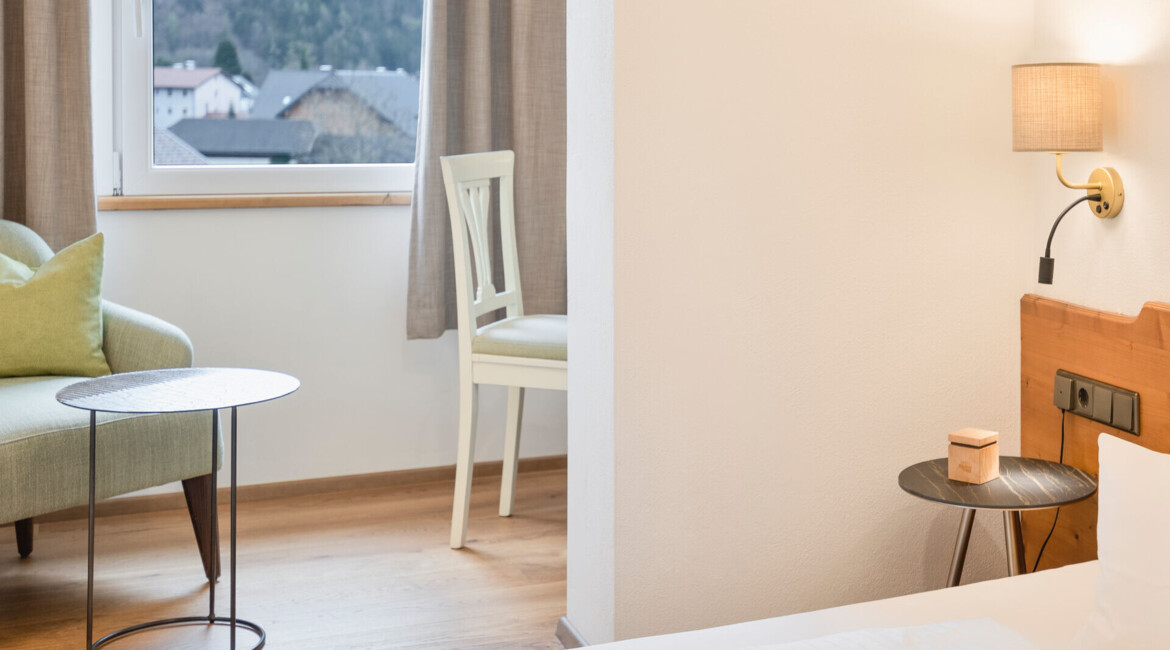 Bright hotel room with a cozy seating area by the window, offering a scenic view of the mountains.