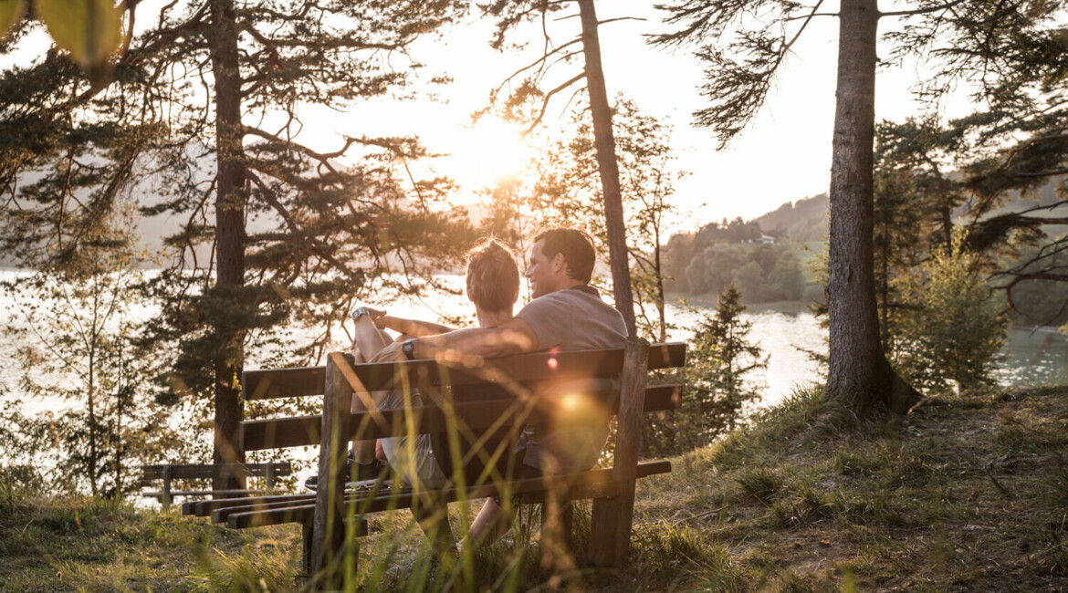 A couple sits on a bench overlooking lake Fuschl.
