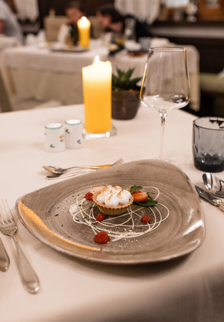 Elegant dessert on a unique plate, elegantly set table with candlelight ambiance in a sophisticated restaurant setting.