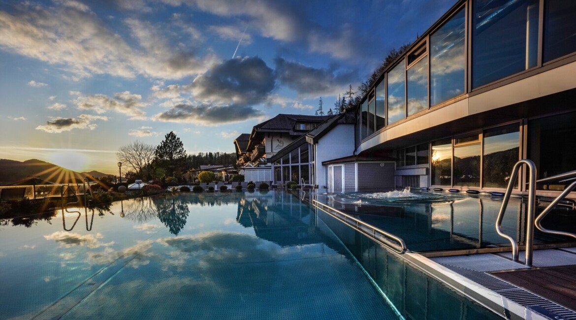 Außenpool des 4*S Wellnesshotel Waldhof Fuschlsee Resort bei Sonnenuntergang.