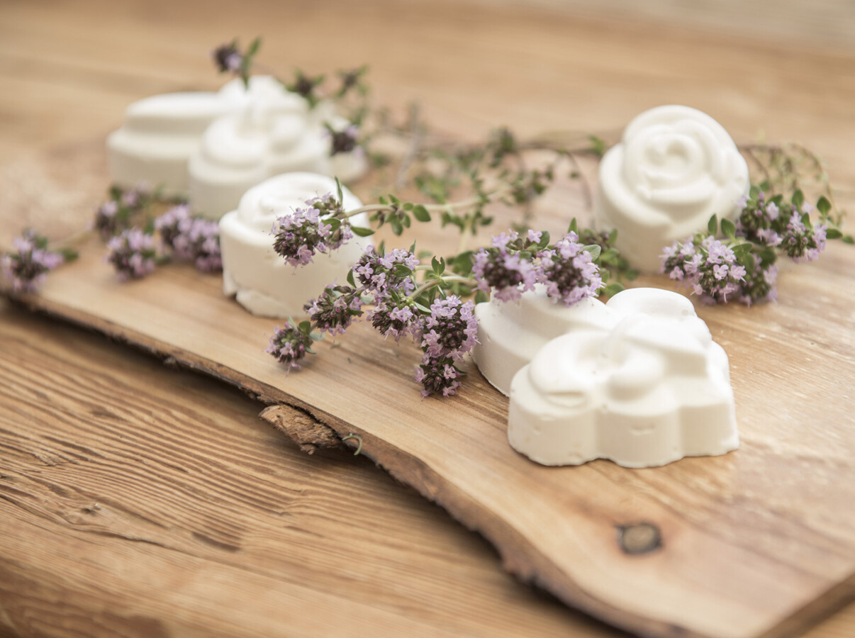 Decorative white soaps with purple flowers on a wooden board, creating a natural and rustic presentation.