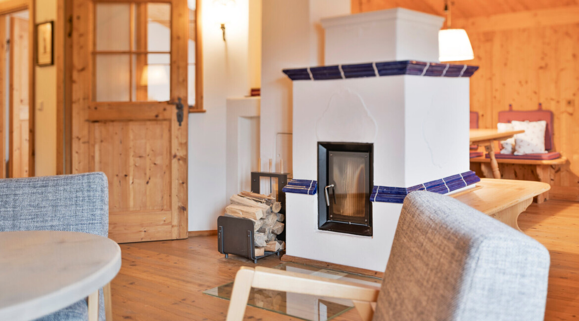 Cozy alpine interior with wooden furniture, a modern fireplace, and a stack of firewood, creating a warm and inviting atmosphere.