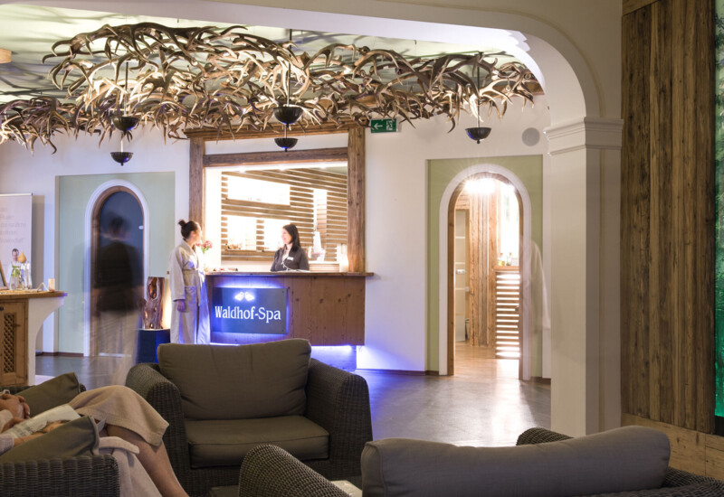 Reception area of Waldhof Spa with a rustic, elegant design featuring antler decor and comfortable seating, creating a welcoming ambiance.