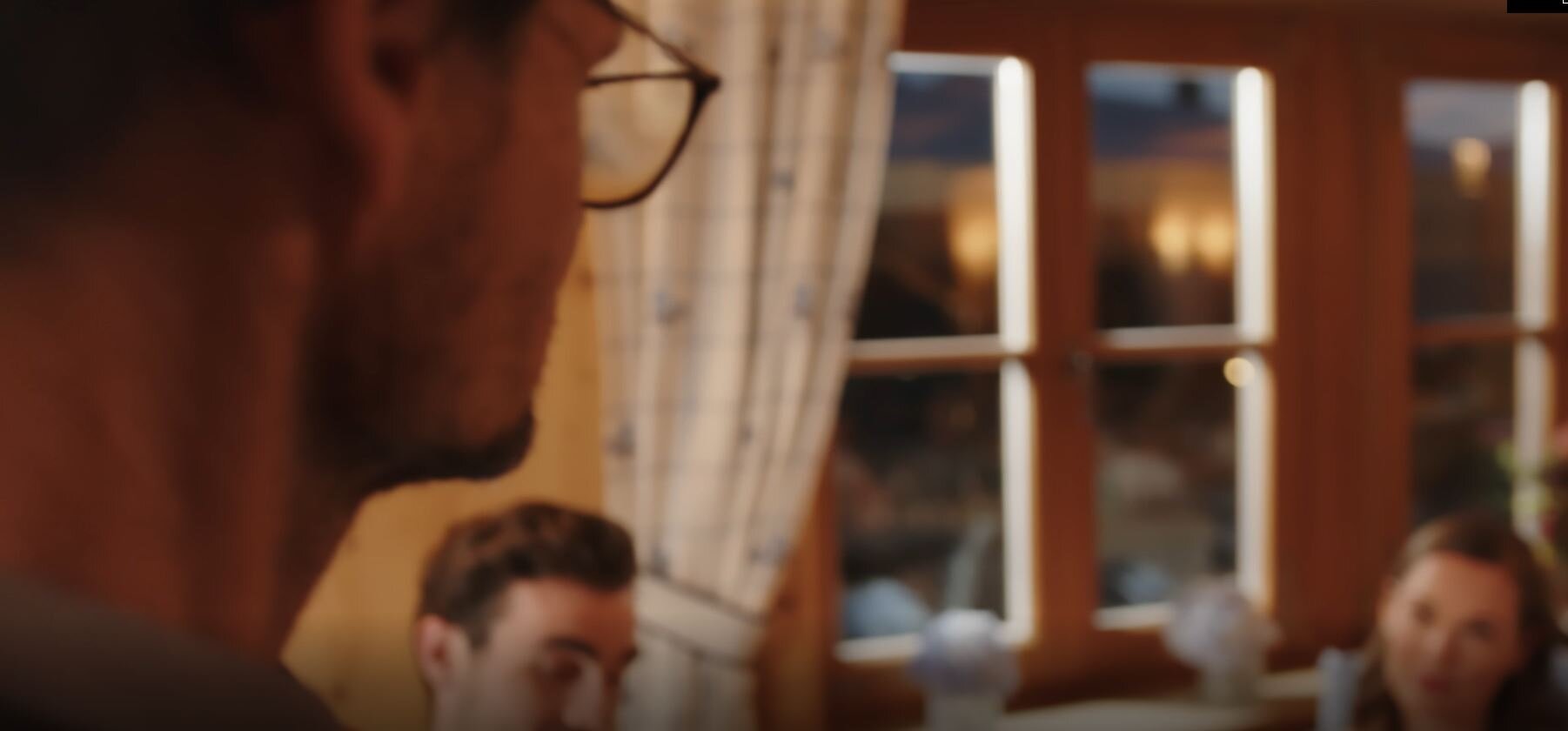 A cozy indoor setting with people conversing near a window.