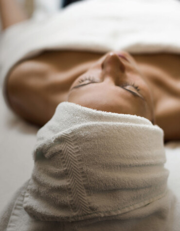 Person relaxing with a towel on their head, lying on a spa bed.