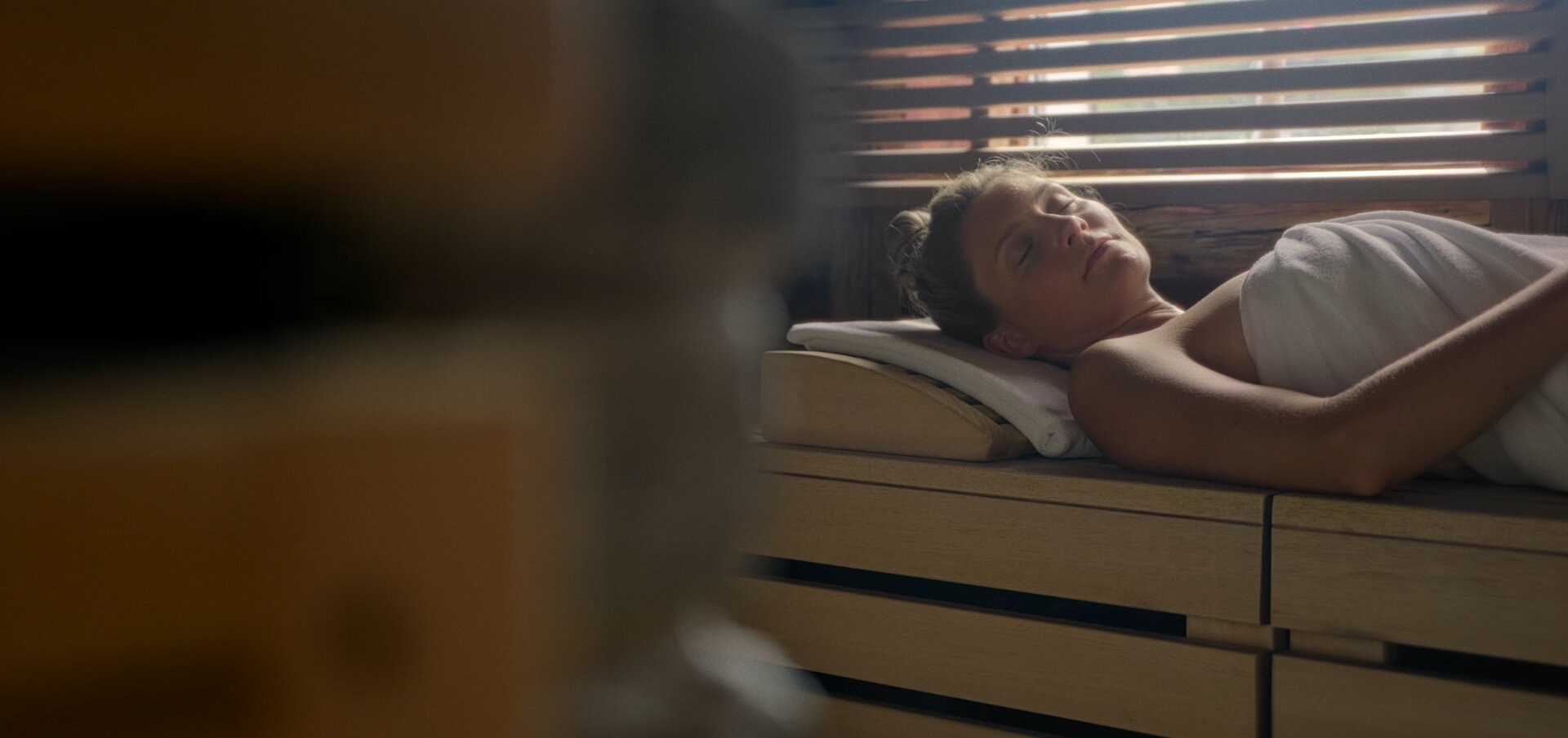 A person relaxing in a sauna wrapped in a towel, enjoying a peaceful moment.