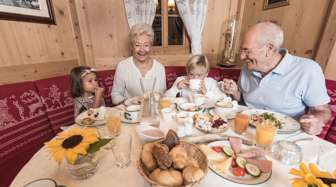 Family enjoying breakfast with a table set with various dishes and drinks.