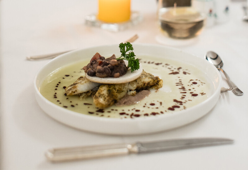 A gourmet dish elegantly plated on a white tablecloth with a lit candle in the background, creating a cozy dining ambiance.