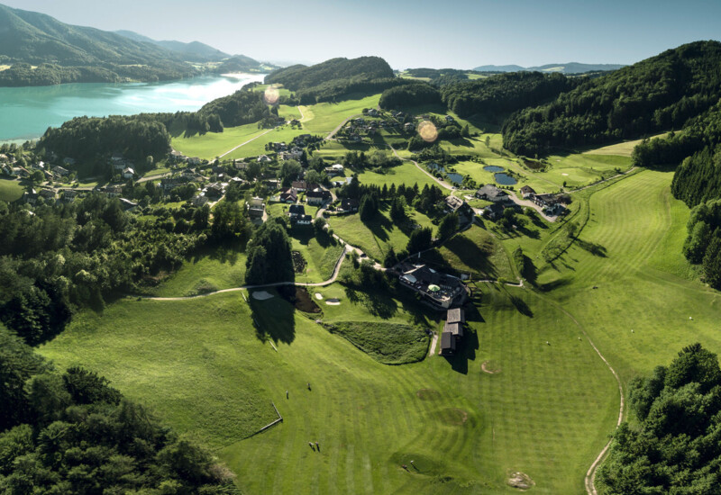 Aerial view of golf course near Waldhof Fuschlsee Resort with lake Fuschl in the background. 