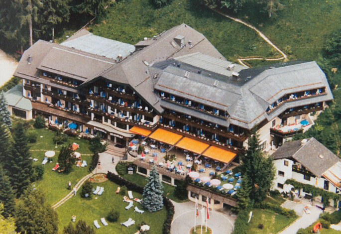 Aerial view of a large hotel with outdoor seating and green surroundings at Waldhof Fuschlsee Resort.