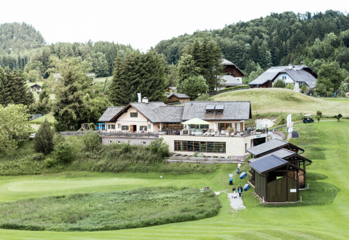 Golf course at Waldhof Fuschlsee Resort with clubhouse and surrounding greenery.