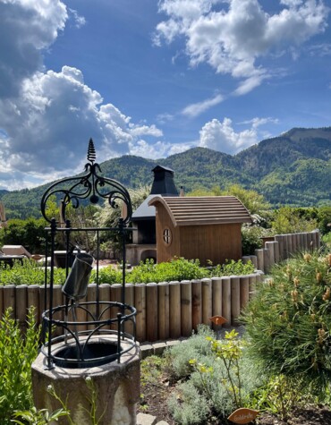 Ein Brunnen im Kräutergarten mit Bergen im Hintergrund.