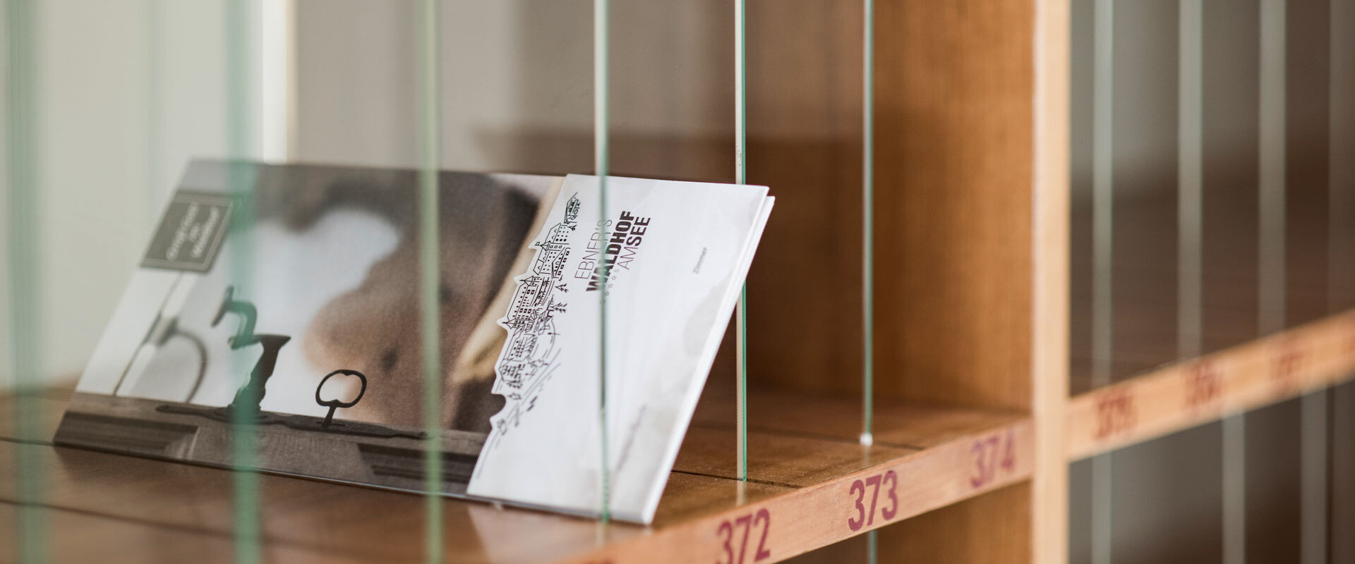A wooden mail slot with numbered compartments holds brochures at a hotel.