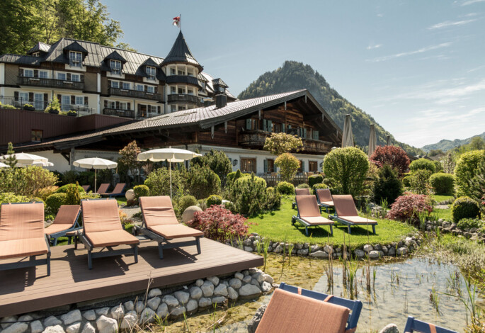 Charming hotel with comfortable lounge chairs amidst lush gardens and scenic mountain views.