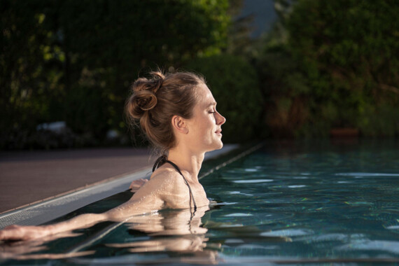 Woman relaxing in the outdoor pool of Waldhof Fuschlsee Resort