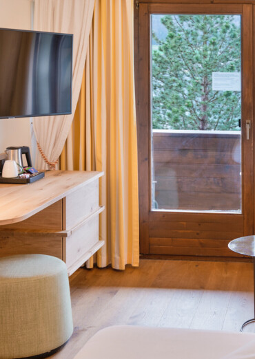 Cozy hotel room with a view of the lake, featuring a TV, lamp, and seating area.