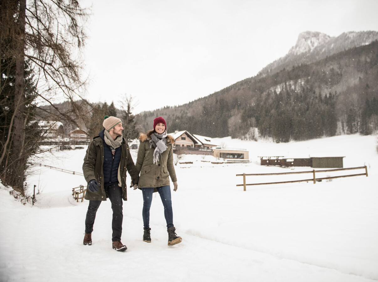 Pärchen beim Winterwandern durch den tief verschneiten Wald am Fuschlsee, Salzburg.
