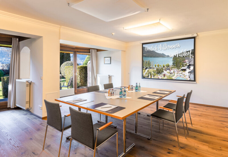 Conference room with a presentation screen displaying "Welcome to Waldhof," featuring a view of the Fuschlsee.