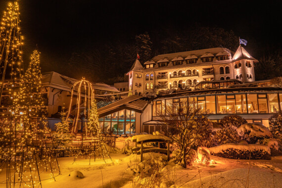 Blick auf den tief verschneiten Waldhof im Winter bei Abendstimmung.