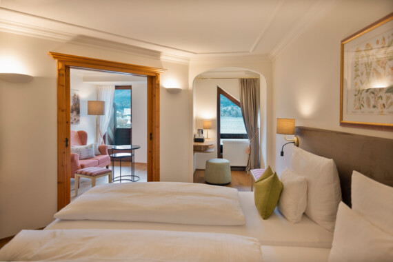 Hotel room at Waldhof Fuschlsee Resort with double bed, cozy seating area, soft lighting, and scenic window view.