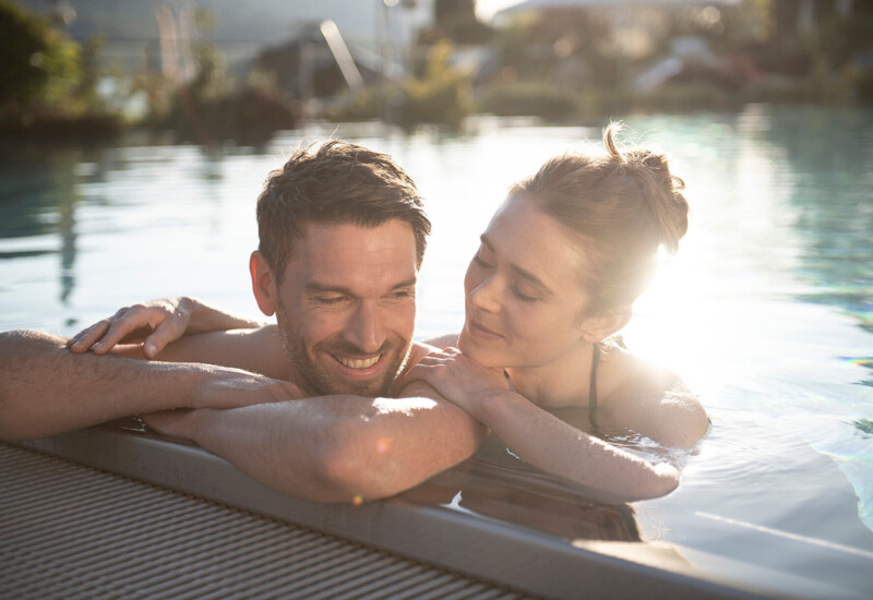 Couple relaxing in an outdoor pool at Waldhof Fuschlsee Resort.