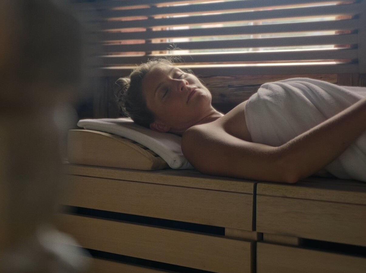 Pärchen im Innenpool des 4 Sterne Superior Wellnesshotel Waldhof Fuschlsee Resort mit Blick auf den Außenpool.