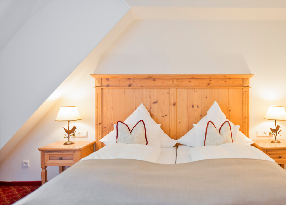 Großzügiges Doppelbett mit Holz in der Osterhornsuite des Hotels Waldhof Fuschlsee Resorts.