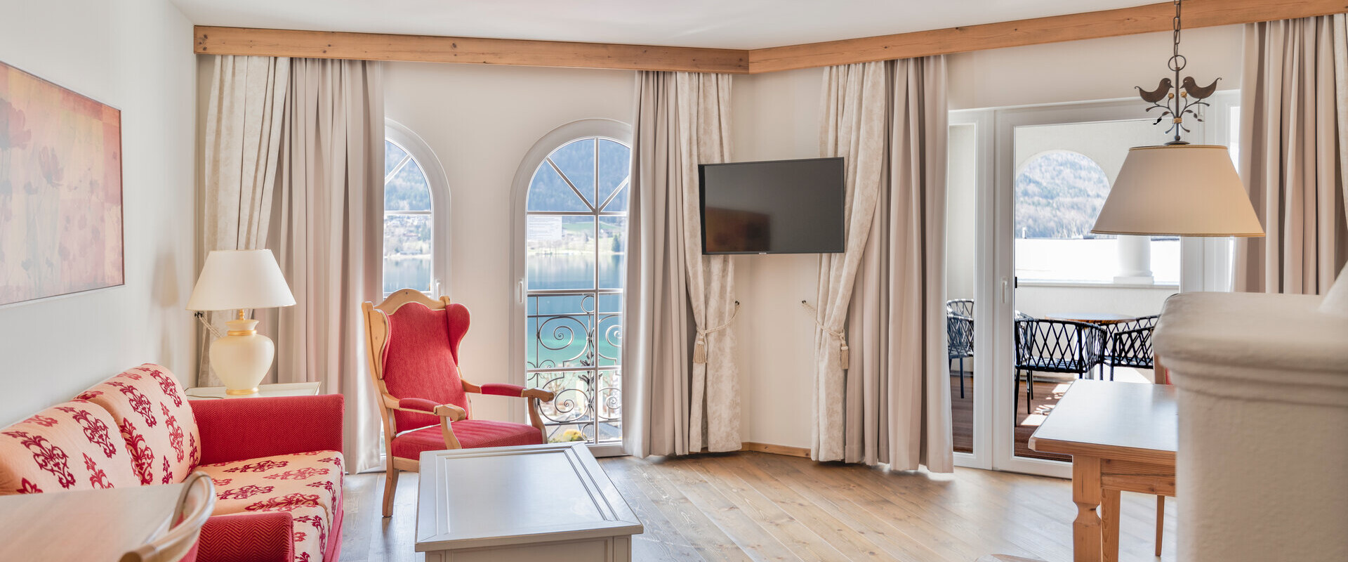 Bright living room with elegant furniture, arched windows, and a view of the lake.