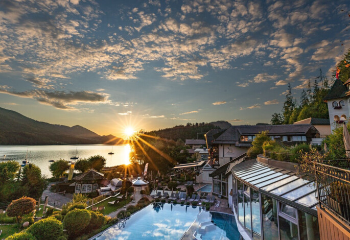 Sonnenuntergang über dem Fuschlsee im Sommer mit Blick auf den Wellnessbereich des Hotel Ebner's Waldhof am See.