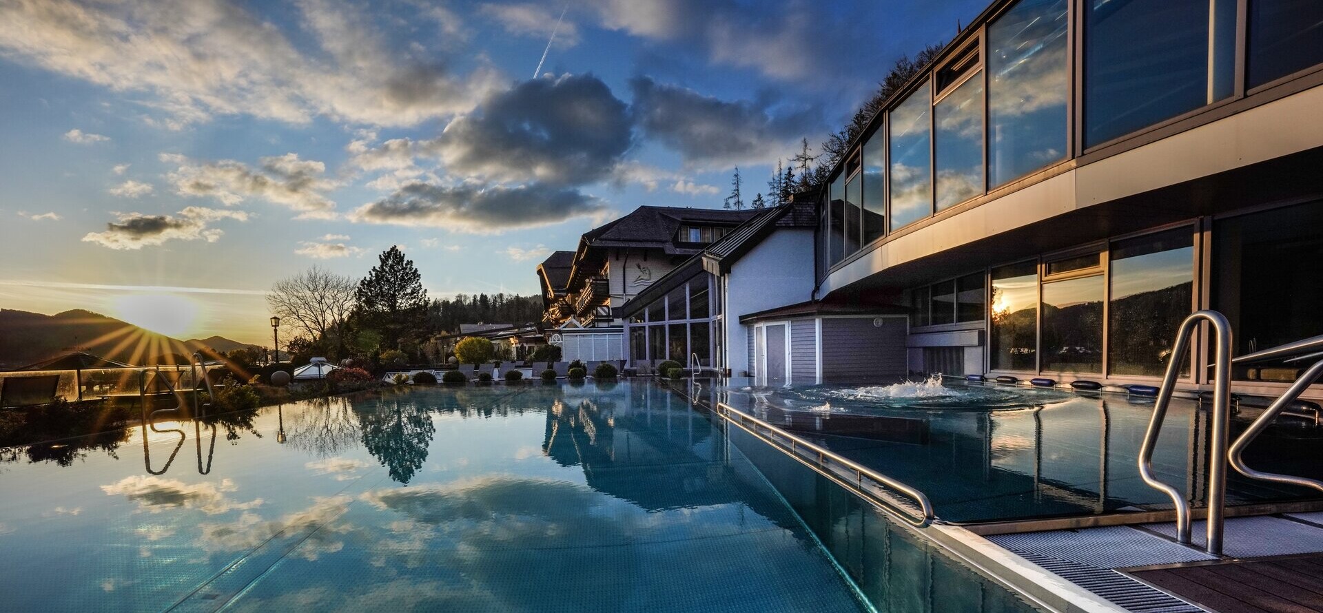 Außenpool des 4*S Wellnesshotel Waldhof Fuschlsee Resort bei Sonnenuntergang.