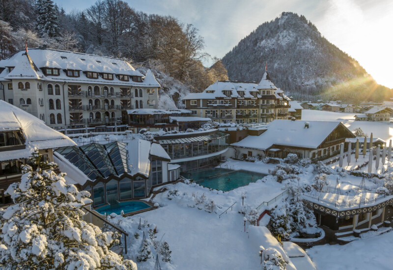 Snow-covered Waldhof Fuschlsee Resort with outdoor pool and mountainous backdrop.