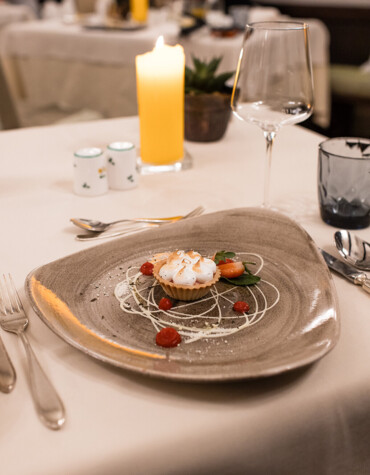 Elegant dessert on a unique plate, elegantly set table with candlelight ambiance in a sophisticated restaurant setting.