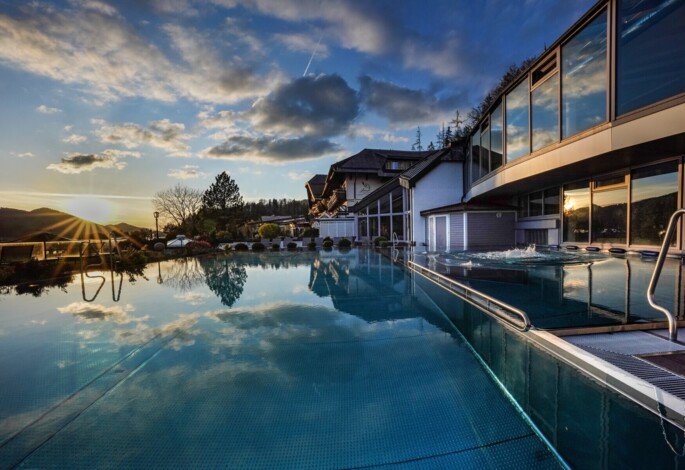 Outdoor pool reflecting the sunset and clouds.