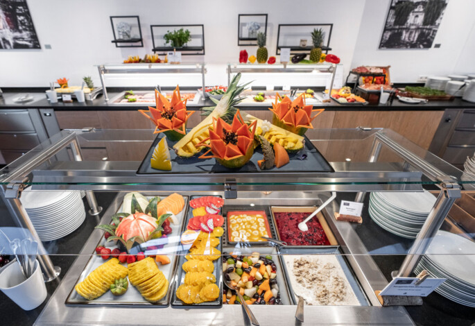 Buffet with a variety of fresh, artistically arranged fruits and desserts, displayed elegantly in a modern dining setting.