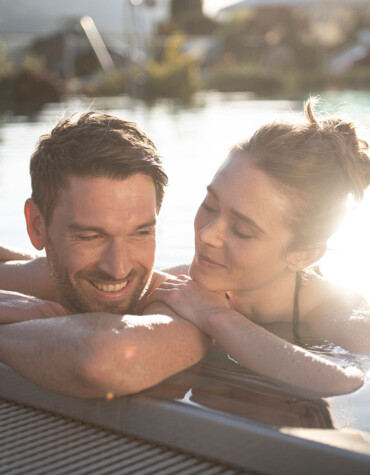 Pärchen beim Genießen der Zweisamkeit im Außenpool des 4*S Wellnesshotel Waldhof Fuschlsee Resort