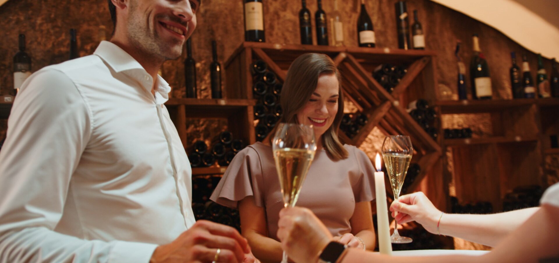 People toasting with champagne in a wine cellar, smiling and enjoying the moment.