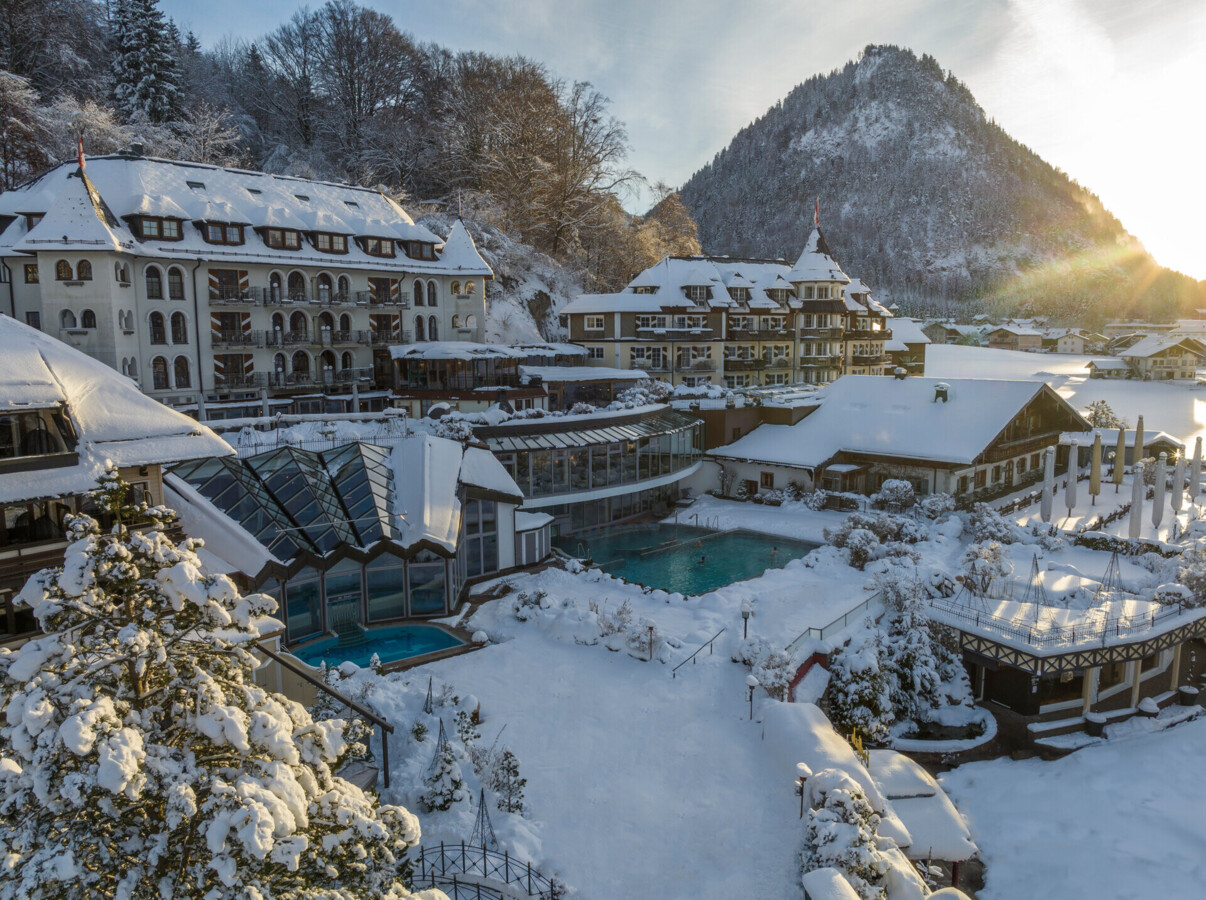 Snow-covered Waldhof Fuschlsee Resort with outdoor pool and mountainous backdrop.