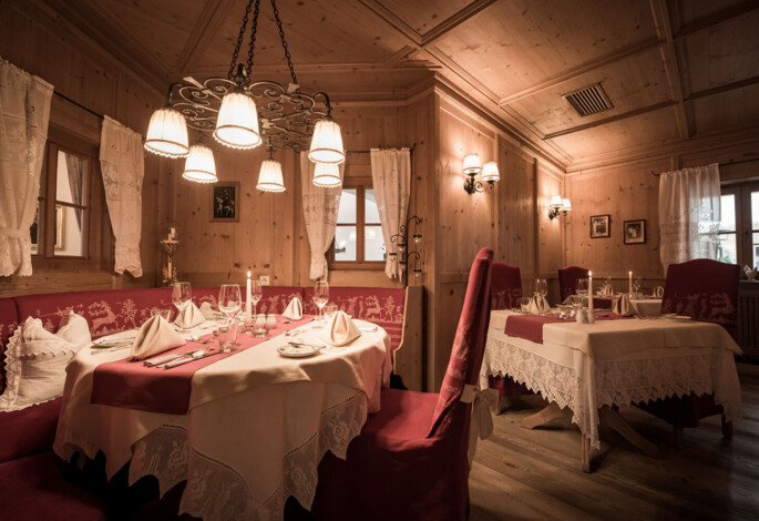 Gemütliches Restaurant mit Holzwänden, elegant gedeckten Tischen und stimmungsvoller Beleuchtung.