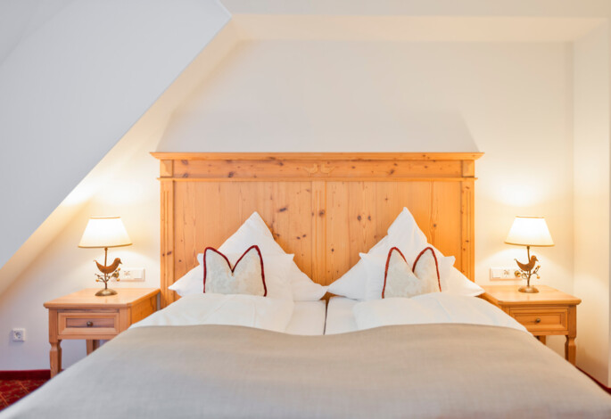 Großzügiges Doppelbett mit Holz in der Osterhornsuite des Hotels Waldhof Fuschlsee Resorts.