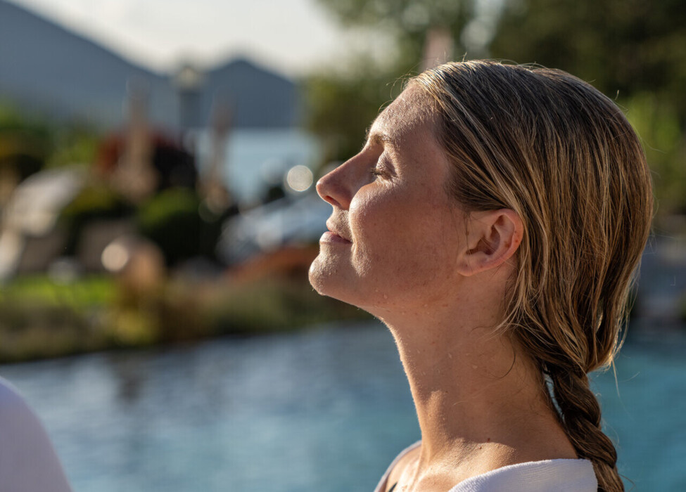 Dame entspannt in der wärmende Sonne am Pool im Hotel Ebner's Waldhof am See.